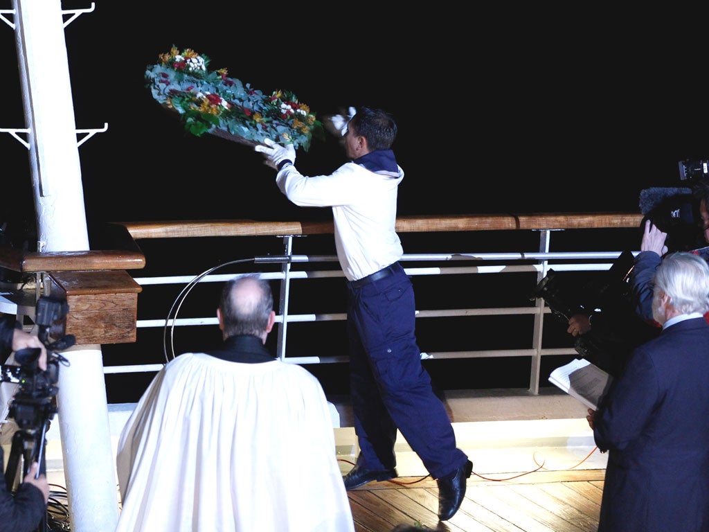 A crew member on the MS Balmoral throws a wreath overboard during a memorial service, marking the 100th year anniversary of the Titanic disaster, in the North Atlantic Ocean