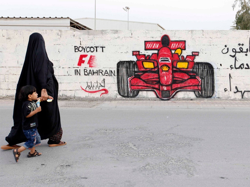 A woman and child pass anti-Formula One graffiti in Bahrain