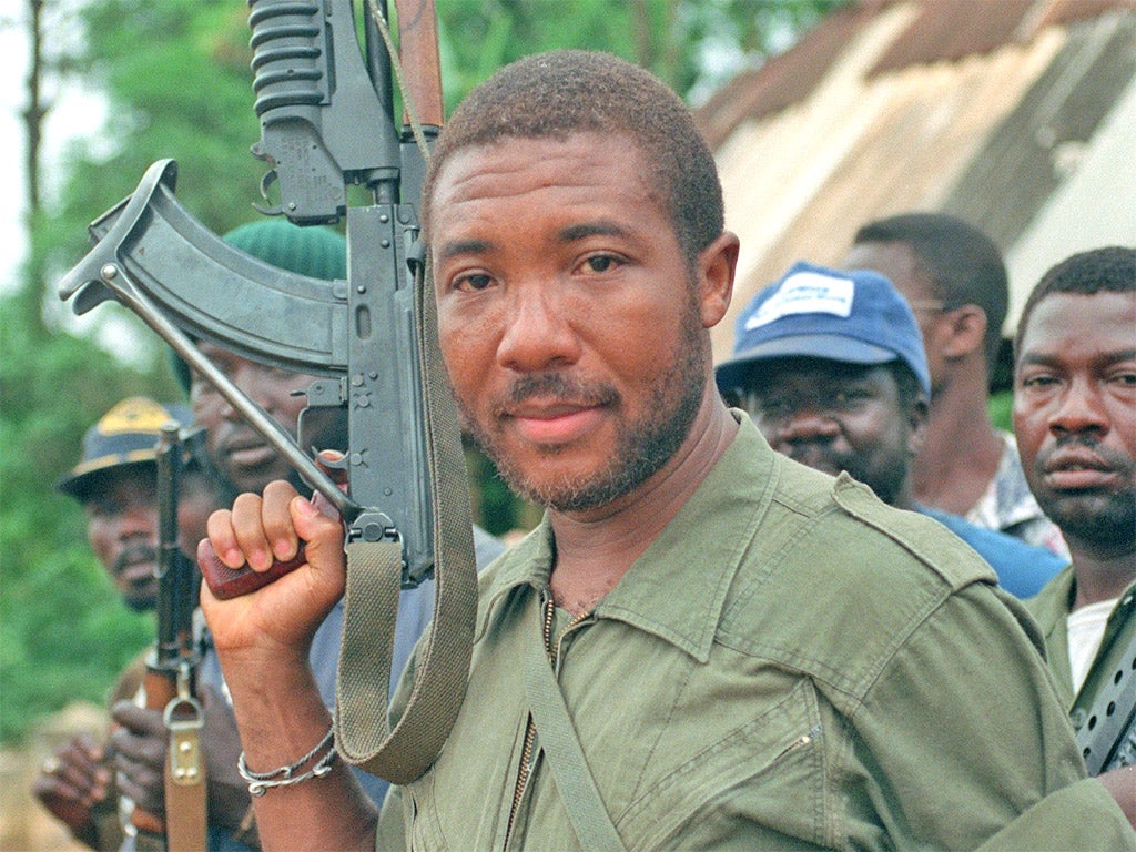 Rebel leader Charles Taylor holds an AK-47 in 1990