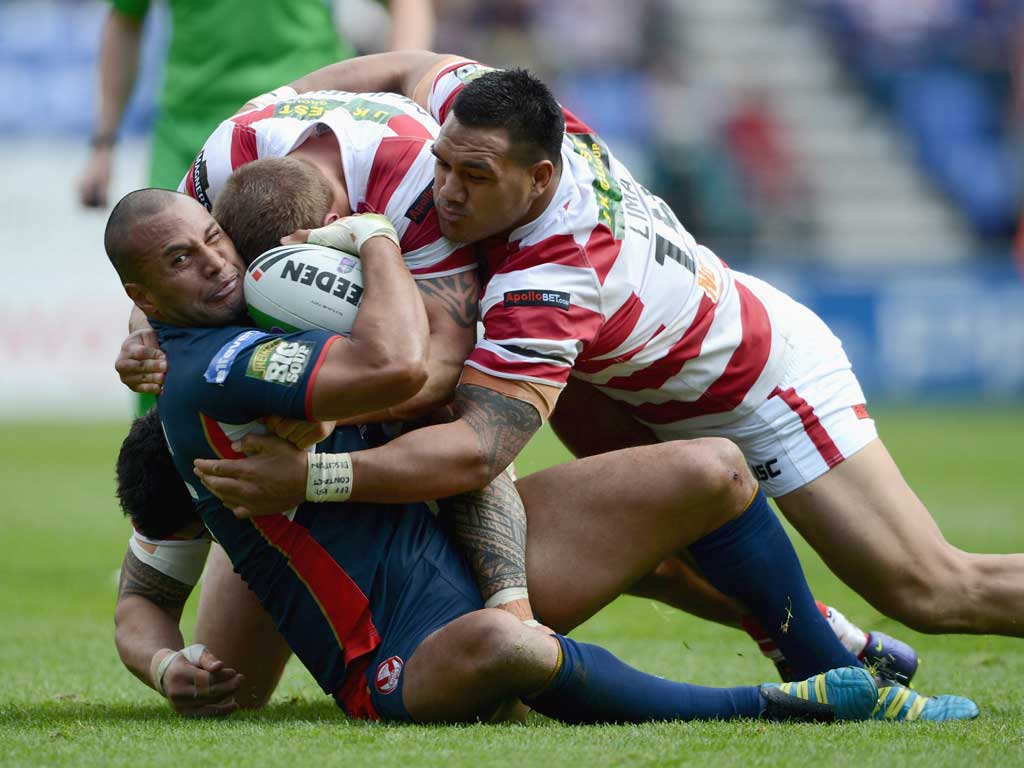 Gone to ground: Francis Meli of St Helens is stopped by Wigan's defence