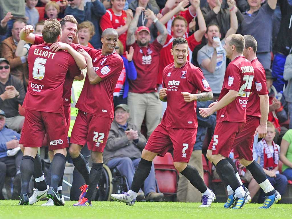 Ben Burgess (second left) is mobbed by his Cheltenham team-mates after heading in the second against Torquay