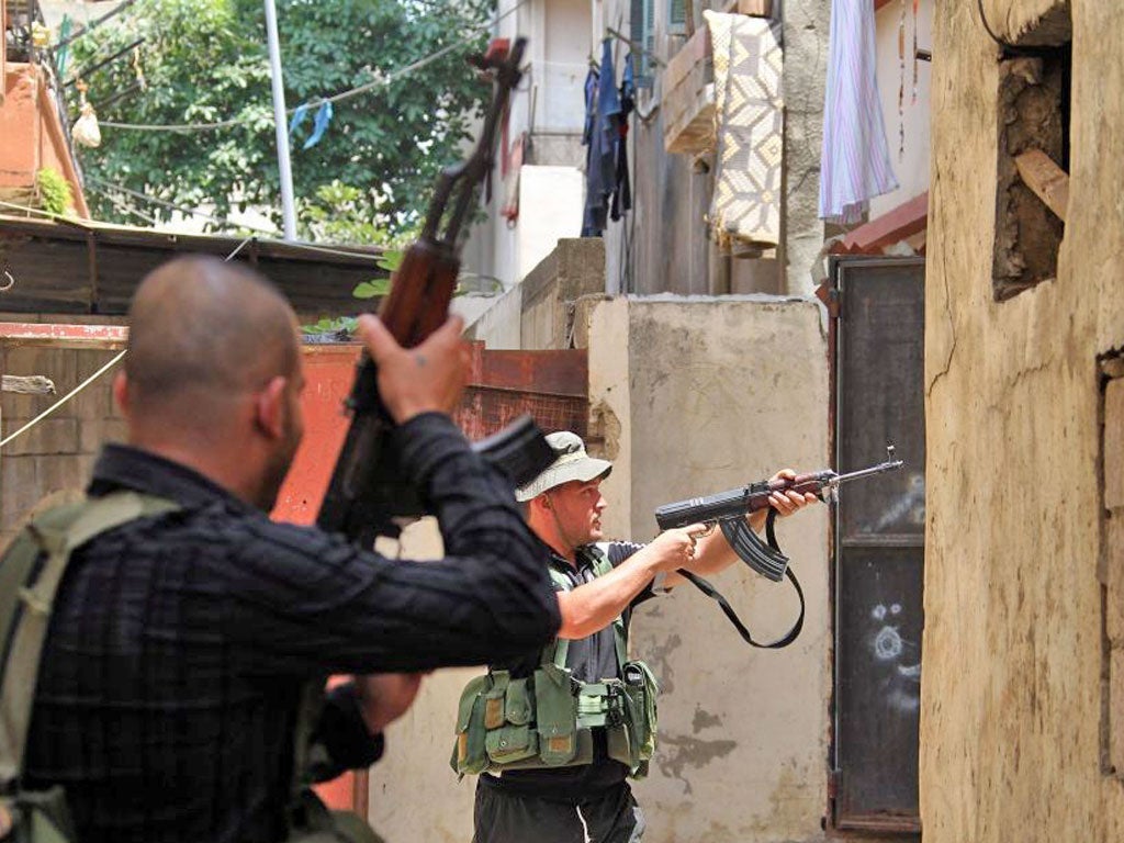 Fighters fire their weapons during clashes in the northern port city of Tripoli, Lebanon between members of the Alawite minority loyal to Syrian President Bashar al-Assad and members of the Sunni majority