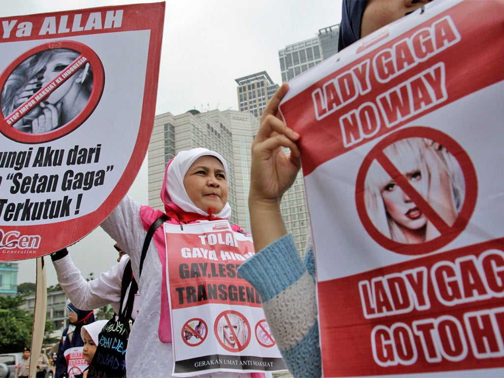 Protesters hold up anti-Gaga posters during a Muslim rally against her concert in Jakarta