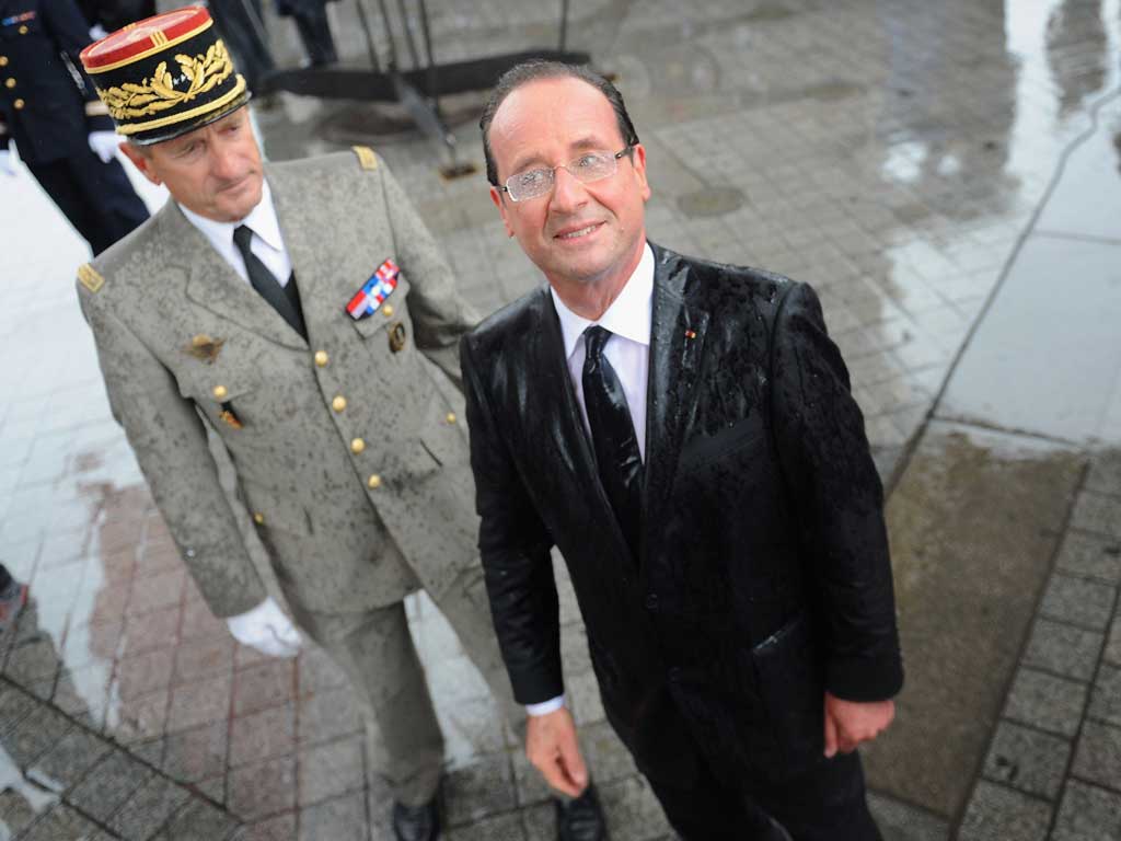 Raining President: A sodden François Holland attends a ceremony at Paris's Tomb of the Unknown Soldier, hours after his inauguration