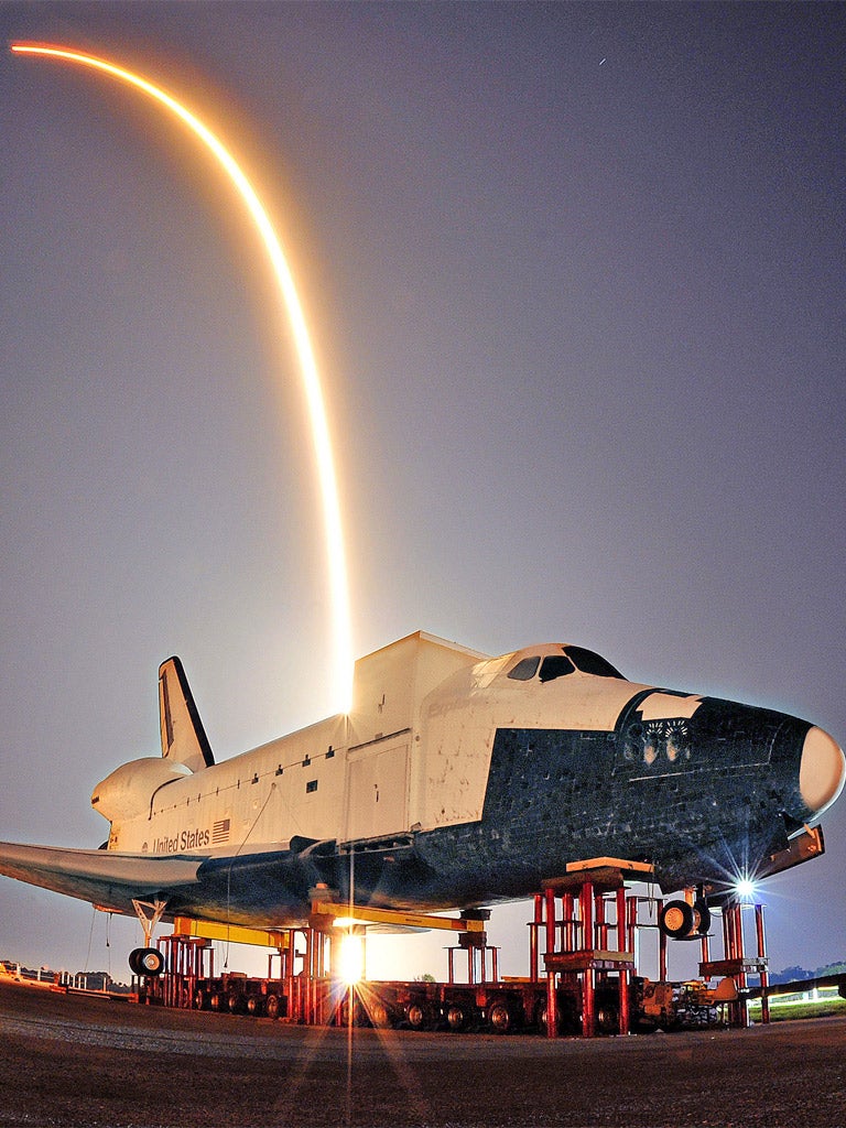The Falcon 9 streaks over a model of Nasa's Space Shuttle at the Kennedy Space Center
