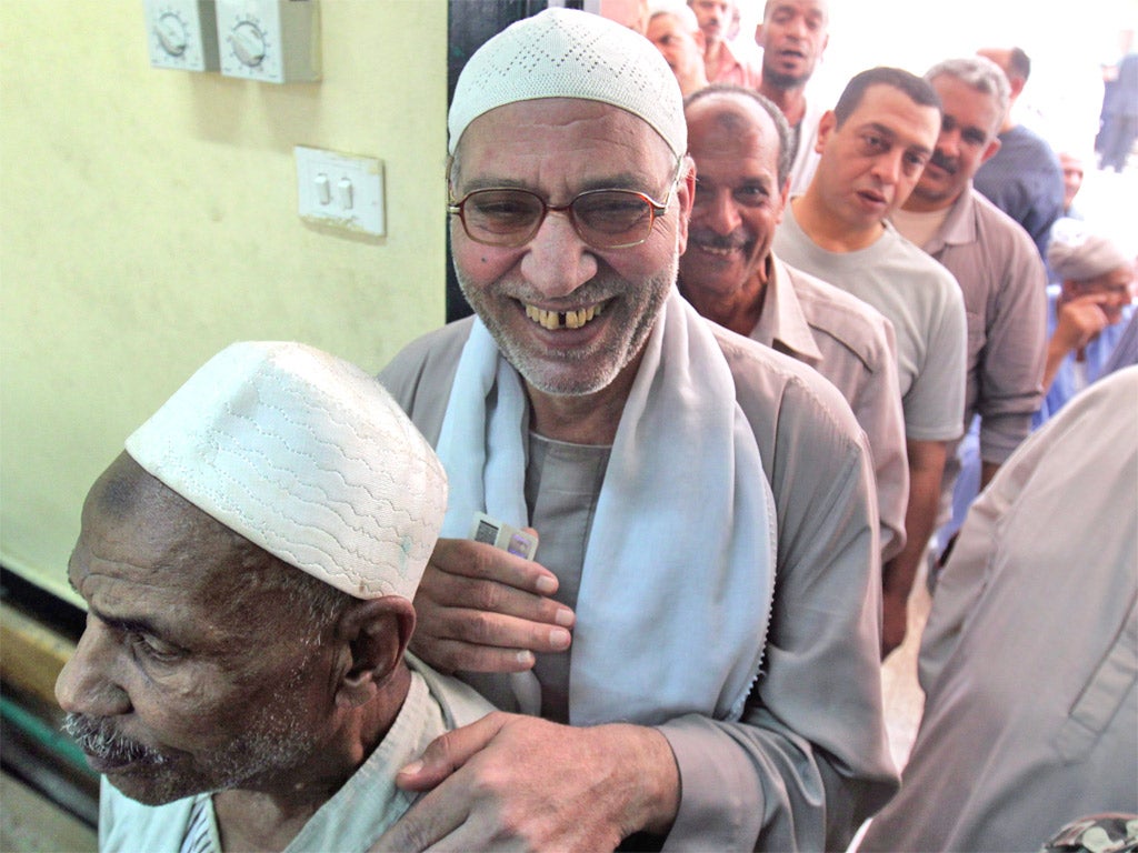 Egyptian men stand in line as they wait to cast their votes at a polling station in Cairo yesterday