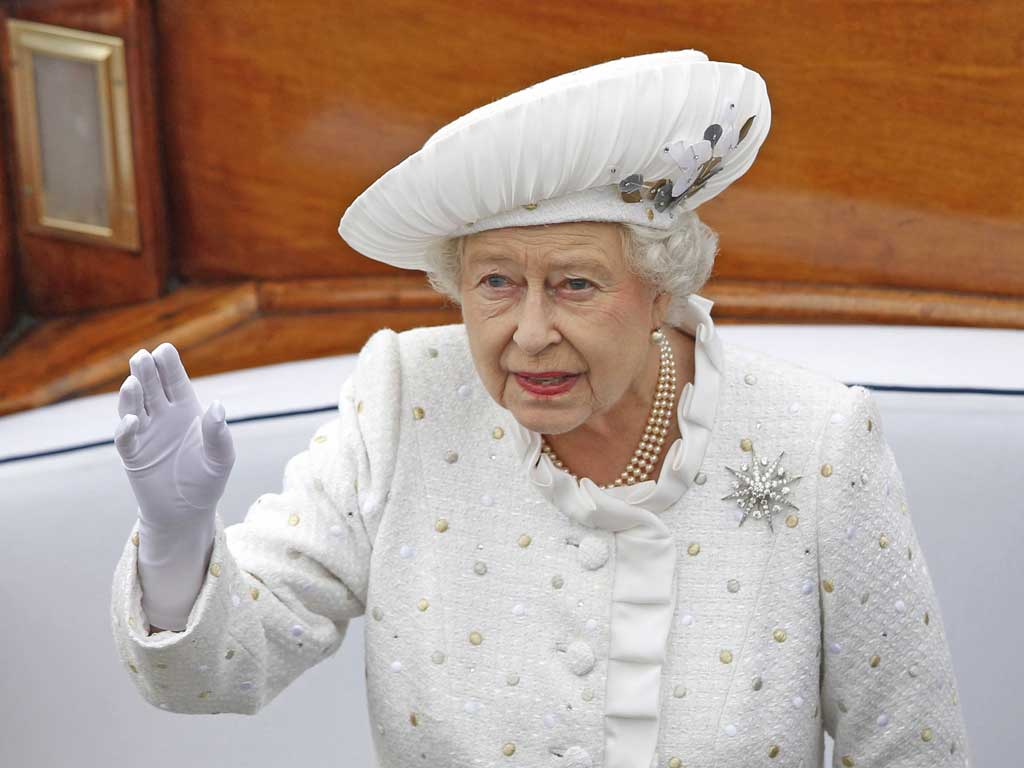 Queen Elizabeth waves from a boat during a pageant in celebration of her Diamond Jubilee along the River Thames