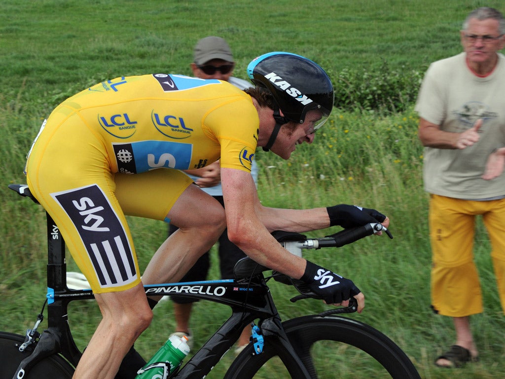 A spectator applauds as Bradley Wiggins grits his teeth in the time trial
