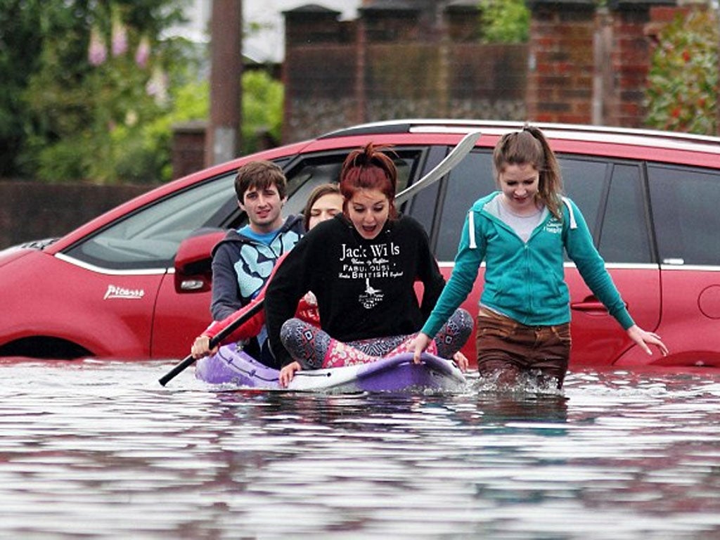 Locals wade through the flood water in a boat along the road in Felpham near Bognor Regis, West Sussex