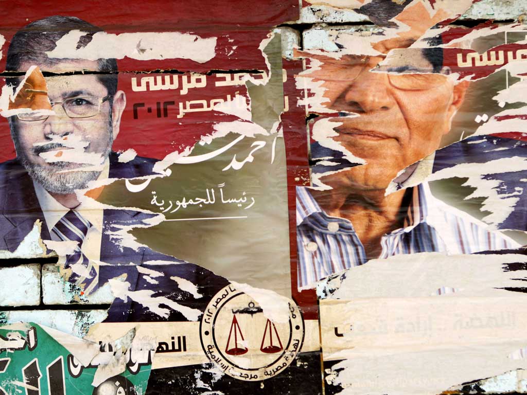 Torn posters of the presidential candidates Mohamed Morsi, left, and Ahmed Shafik adorn a wall near a polling station in Cairo yesterday