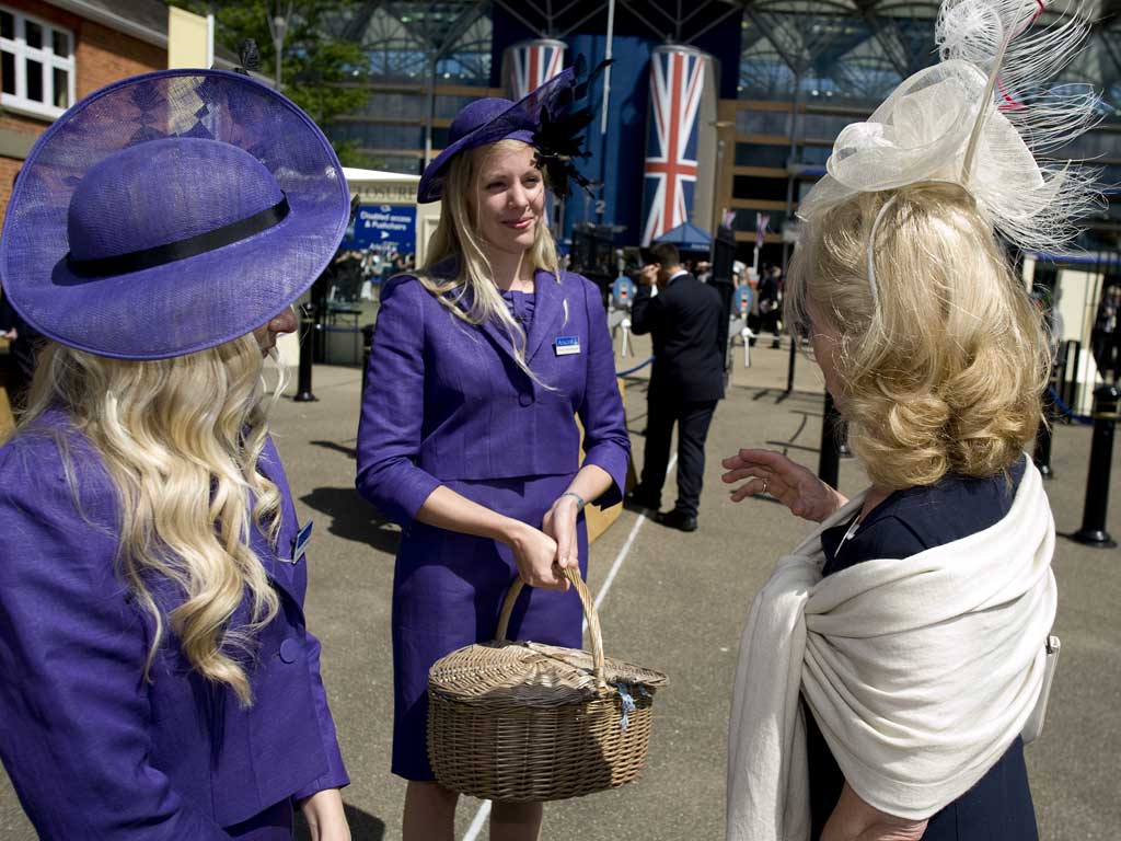 Two dress code assistants chat with a racegoer before she enters the grandstand