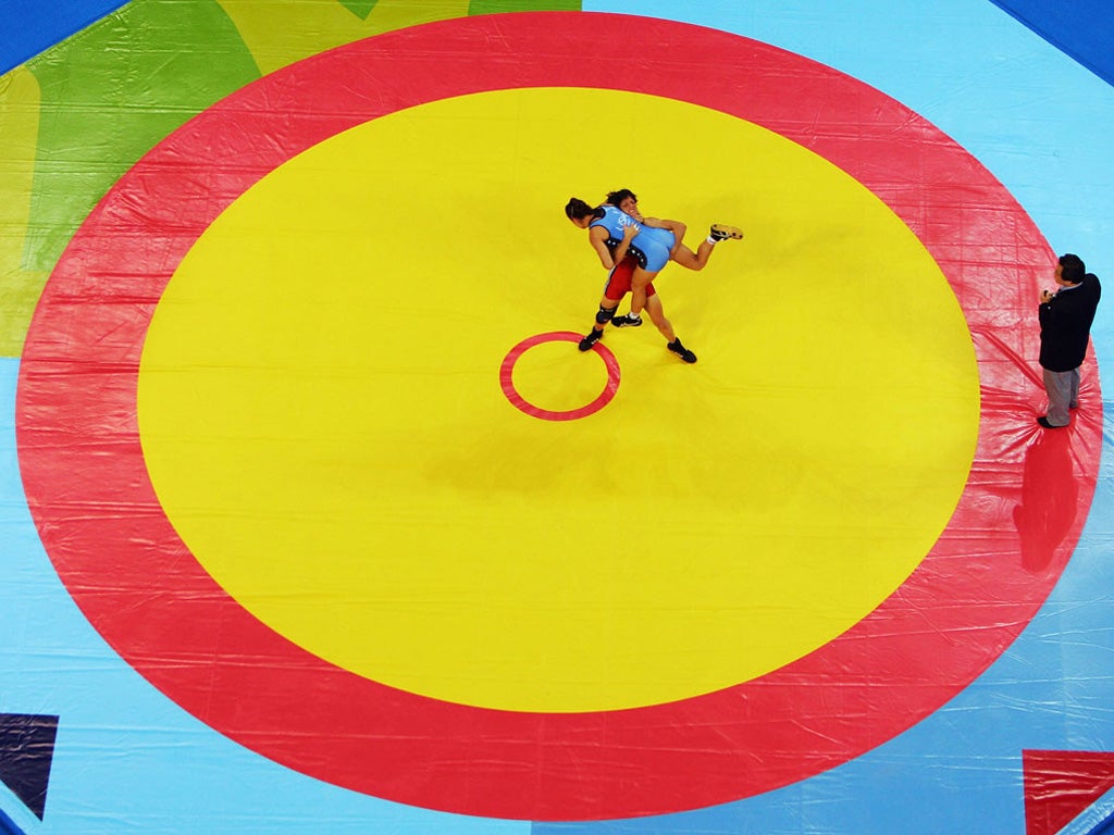 Bullseye! Seen from above by photographer Al Bello, the women's freestyle wrestling seems to swing inevitably inwards to that centre spot. Stavroula Zygouri of Greece heaves the USA's Sara McMann into the air, legs waving, at the 2004 Athens Games.