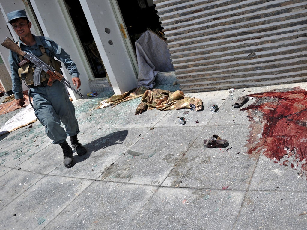 An Afghan policeman walks at the Spozhmai Hotel in Qargha lake on the outskirts of Kabul following the attack