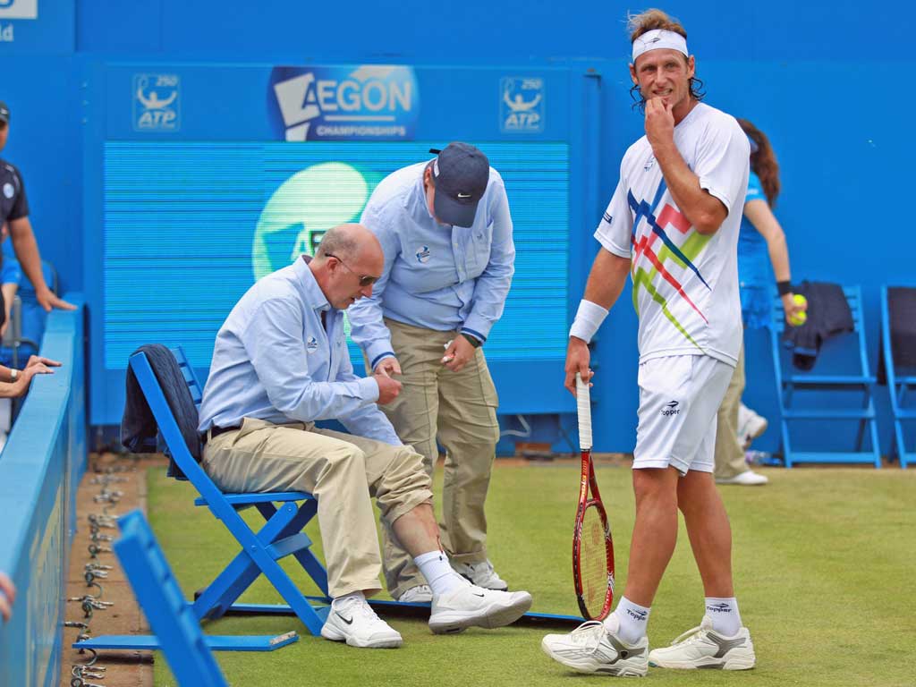 David Nalbandian looks sheepish after injuring the line judge