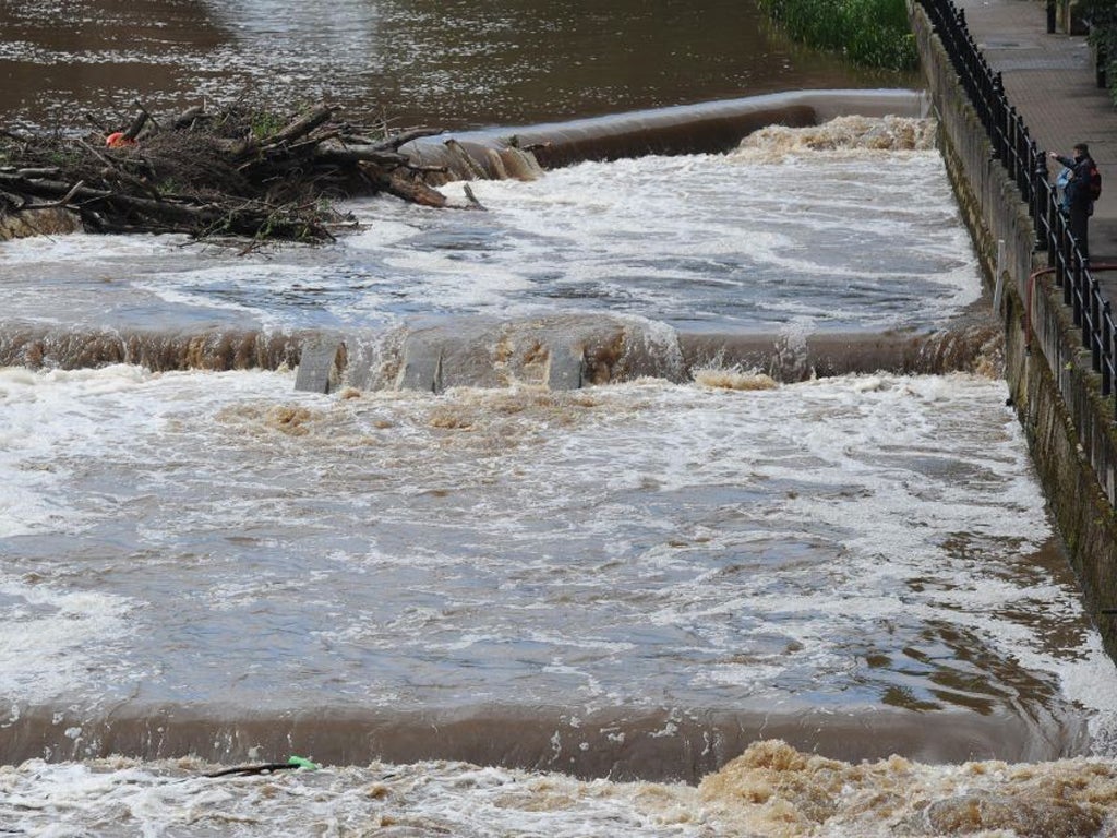 People look out over the fast flowing River Wear in Durham today