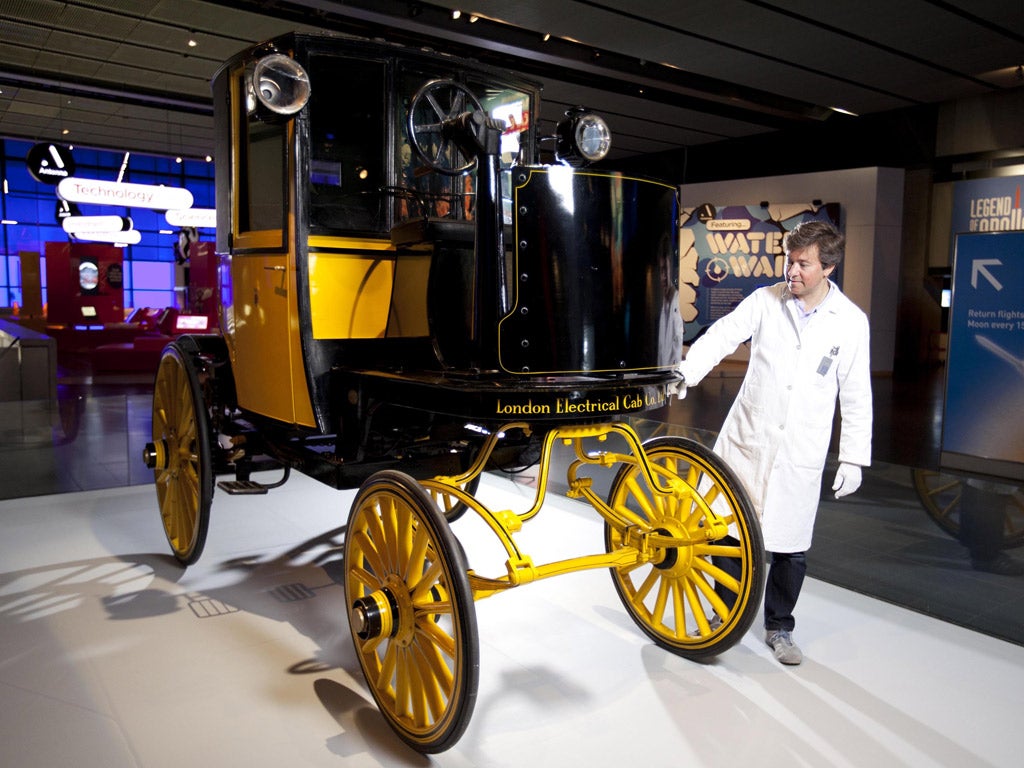 Conservator Richard Horton cleans the Bersey Cab, London's first electric taxi