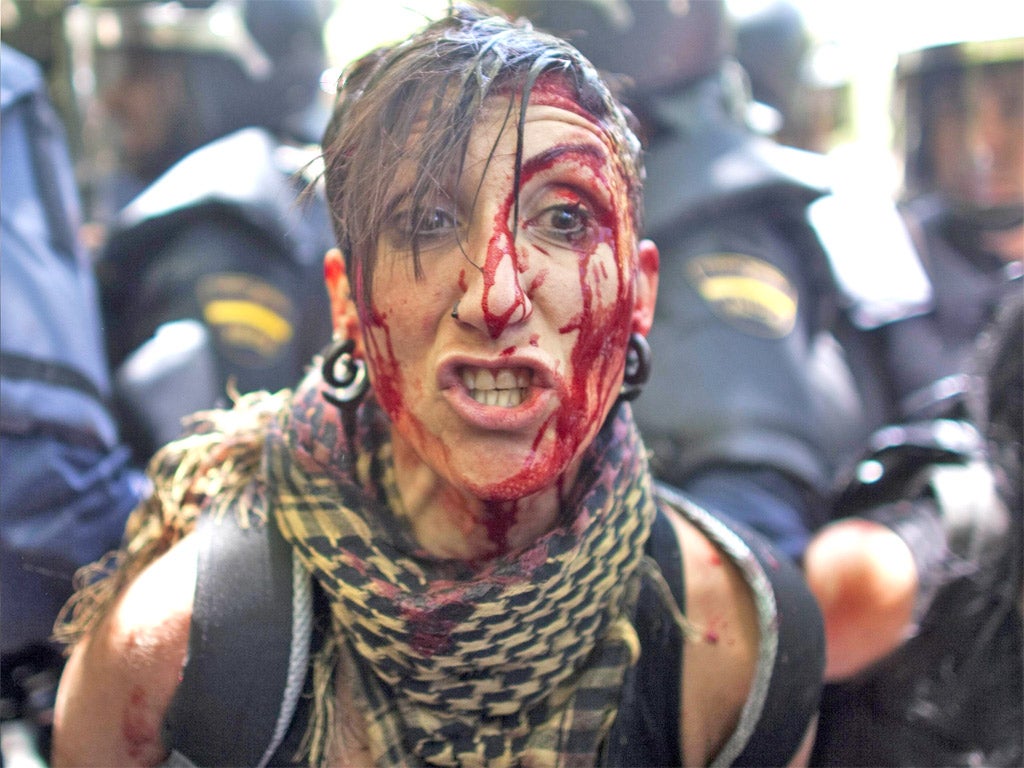 An injured protester is detained by riot police