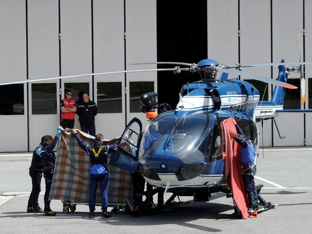 Rescuers use blankets to hide a victim of yesterday's avalanche