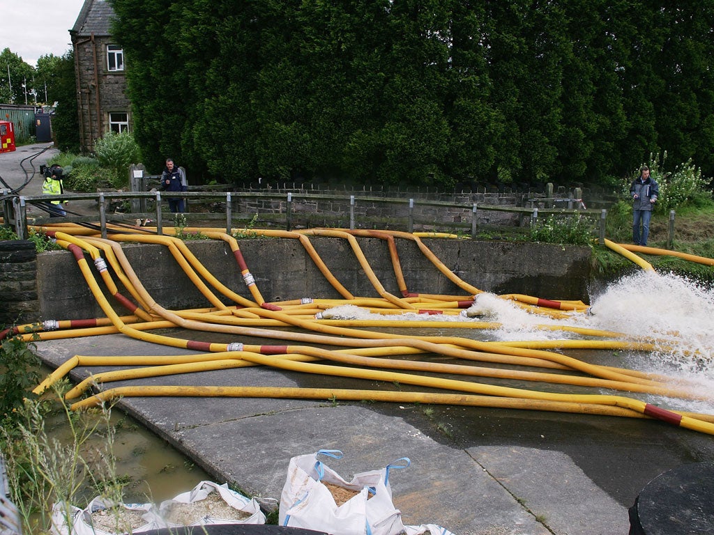 Firefighters and engineers pump water out of the Ulley Reservoir