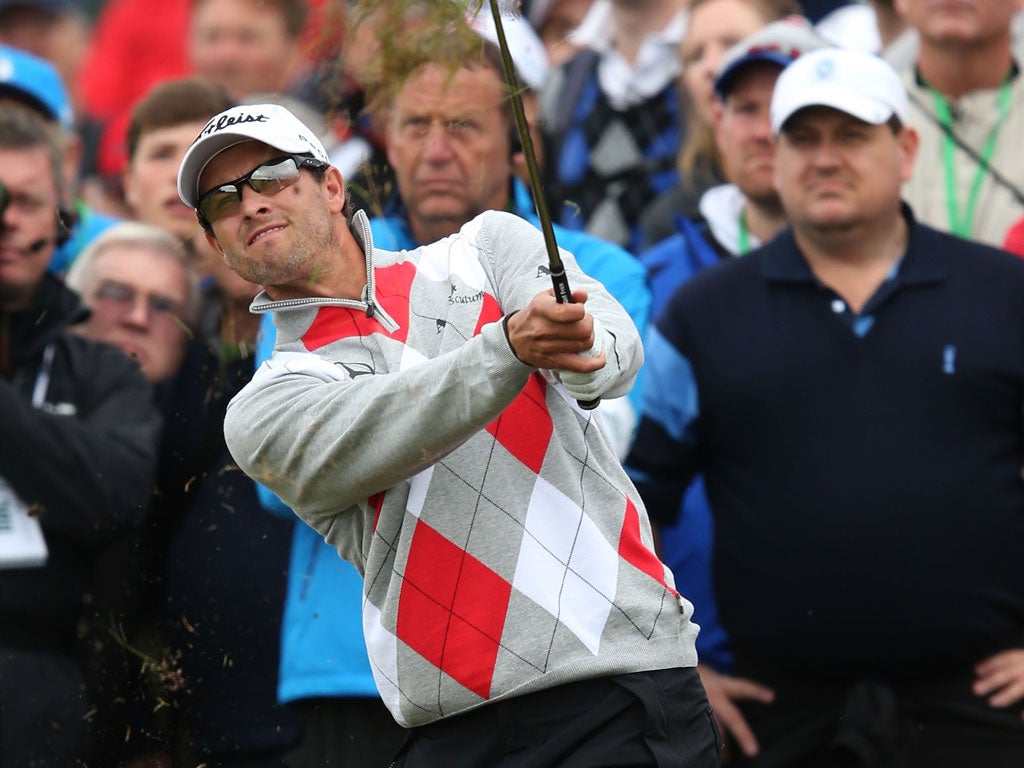 Adam Scott hits out of the rough on the second hole