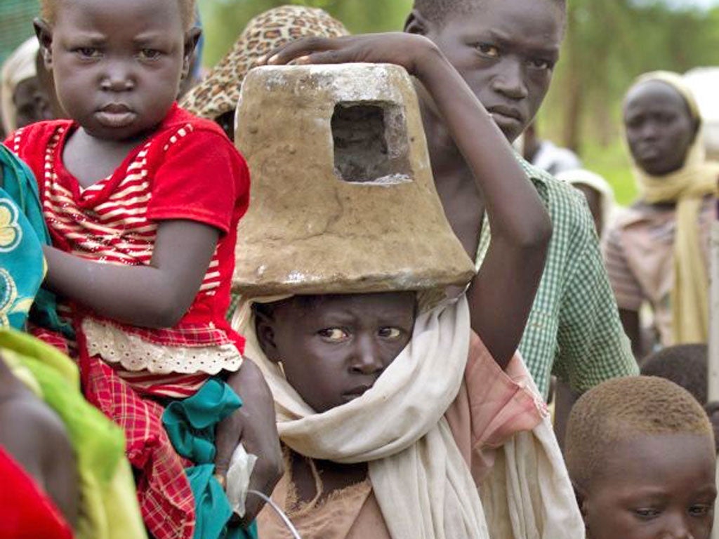 Refugees wait to be moved out of the rain-soaked Jamam camp