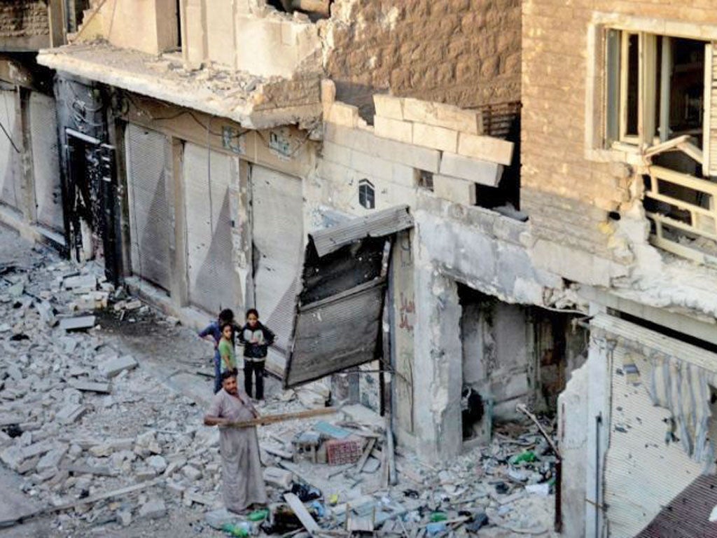 A Syrian family stand in the rubble of destroyed houses in Maarat al-Numaan in Idlib province, northern Syria