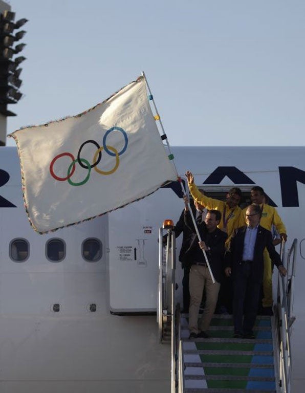 Rio mayor Eduardo Paes waved the five-ringed flag as he and other officials disembarked from the flight that brought them back from London