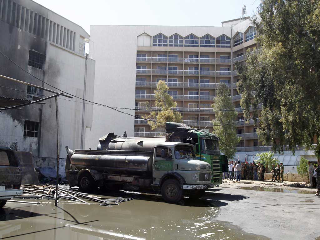 Burnt vehicles are seen after a bomb exploded at a military site near a hotel used by United Nations monitors in Damascus