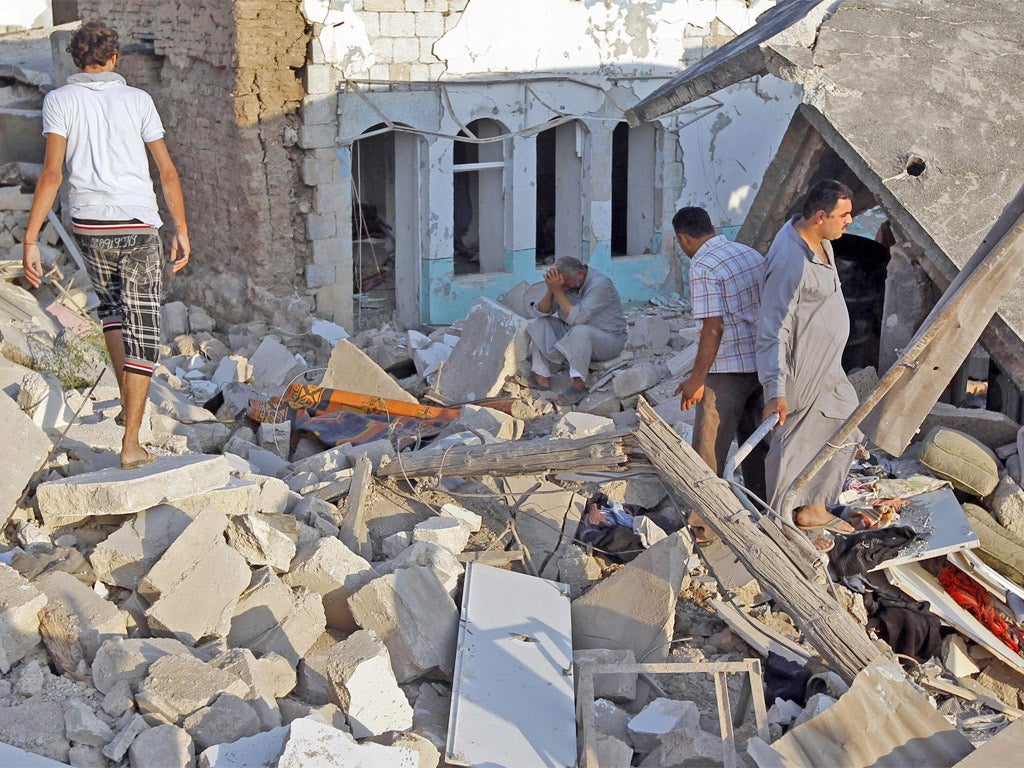 A man cries in front of houses destroyed during the Syrian Air Force air strike in Azaz