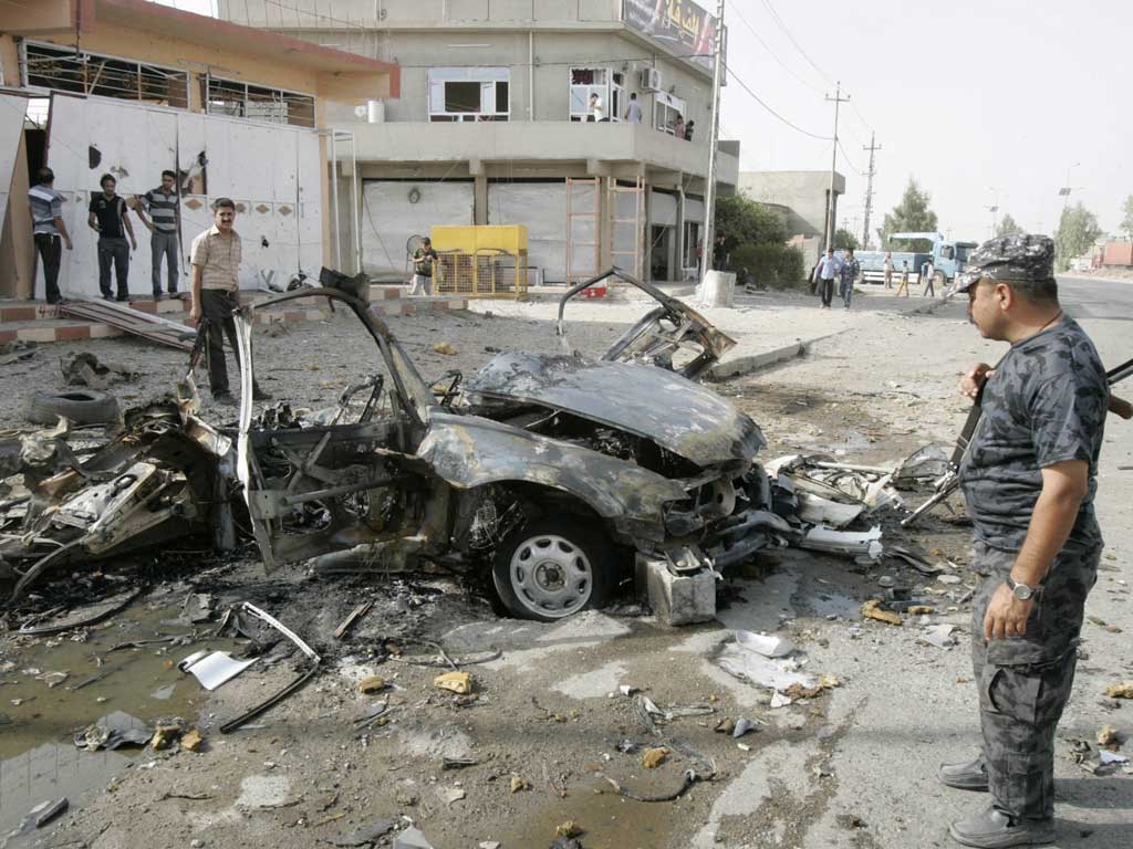 Security personnel inspect the site of a car bomb attack in Kirkuk