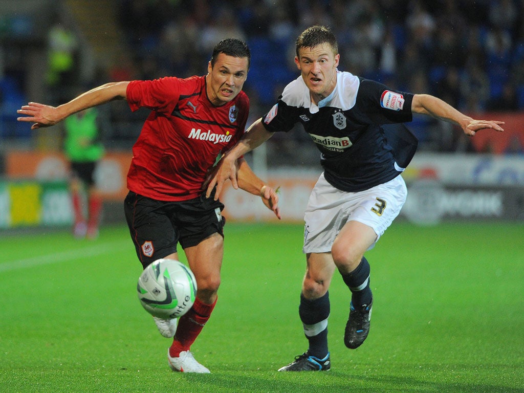 Cardiff's Don Cowie (left) in their controversial red kit and Huddersfield full-back Paul Dixon battle for the ball