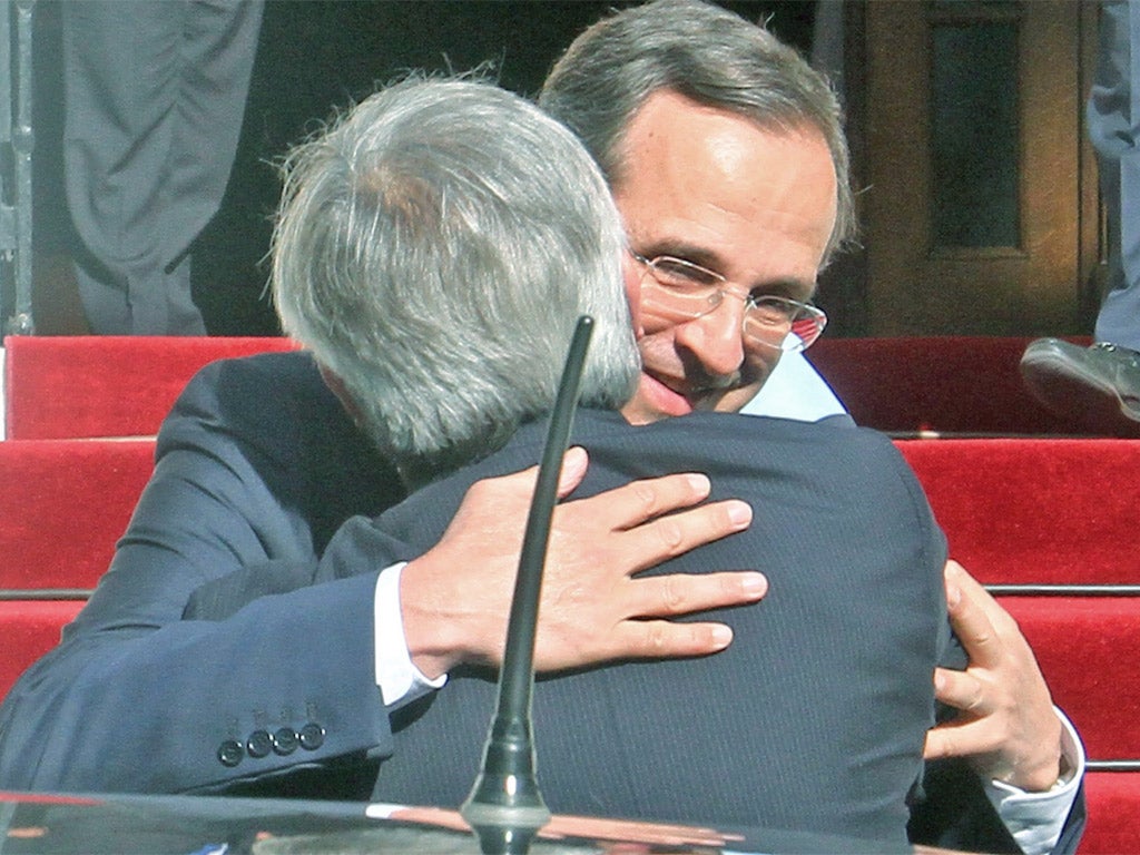 Greek Prime Minister Antonis Samaras embraces Jean-Claude Juncker in Athens yesterday