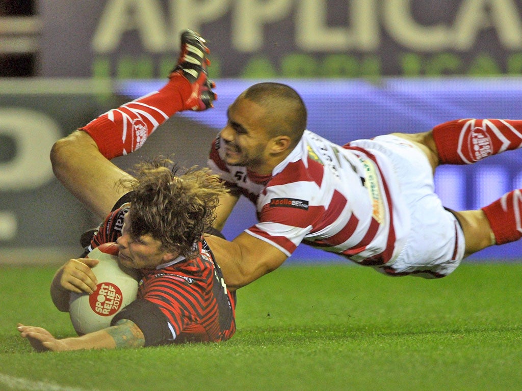 Lee Briers goes over for Warrington despite the efforts of Wigan's Harrison Hansen