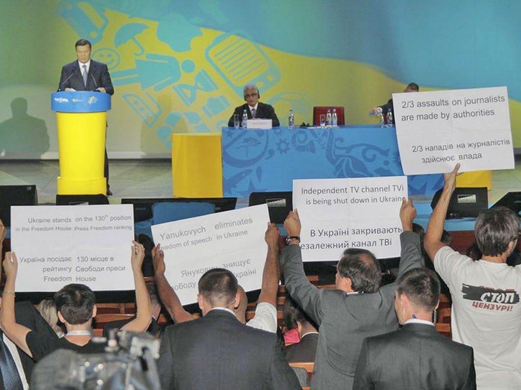 Journalists hold up placards in front of Viktor Yanukovich