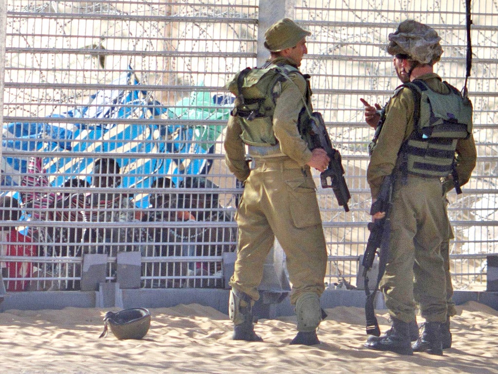 African refugees sit behind a border fence in Israel on Tuesday