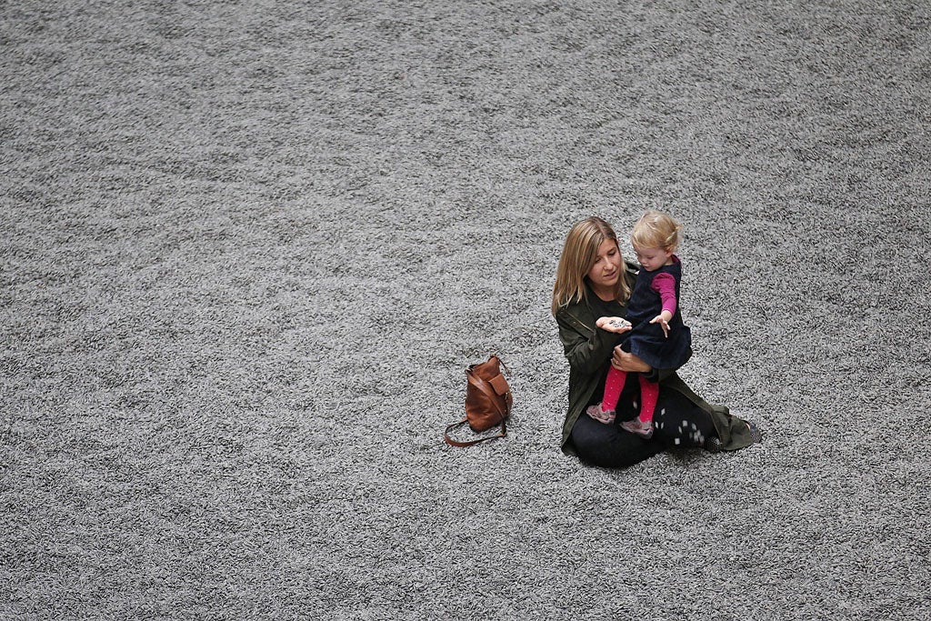 A mother show's her toddler Ai Weiwei's sunflower seed installation at Tate Modern