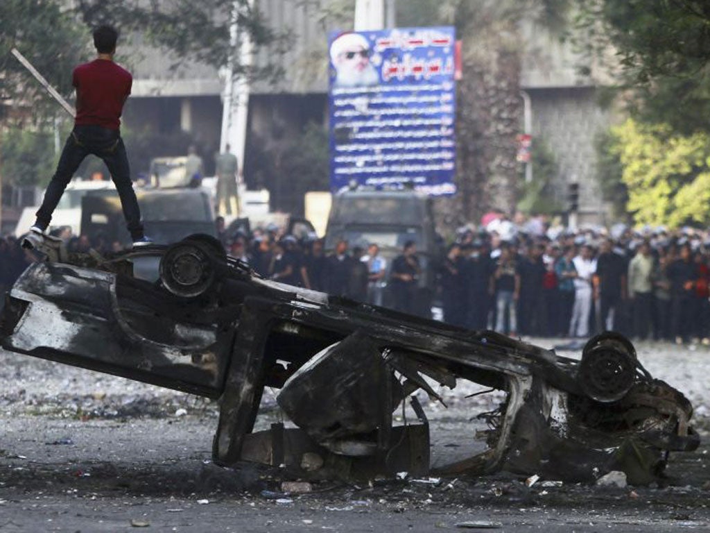 Egypt: An Egyptian protester stands on top of a burnt out car