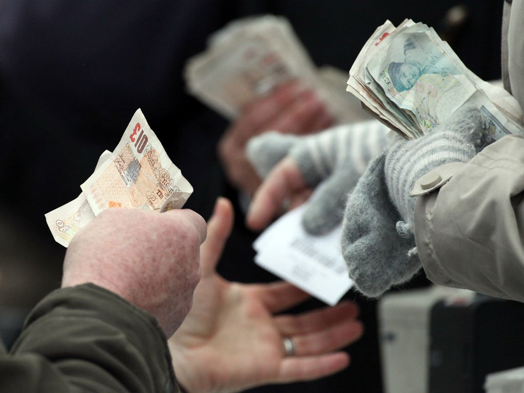 CHELTENHAM, ENGLAND - MARCH 16: Money changes hands as horse racing fans place bets on the Cheltenham Gold Cup at the Cheltenham Festival 2012 on March 16, 2012