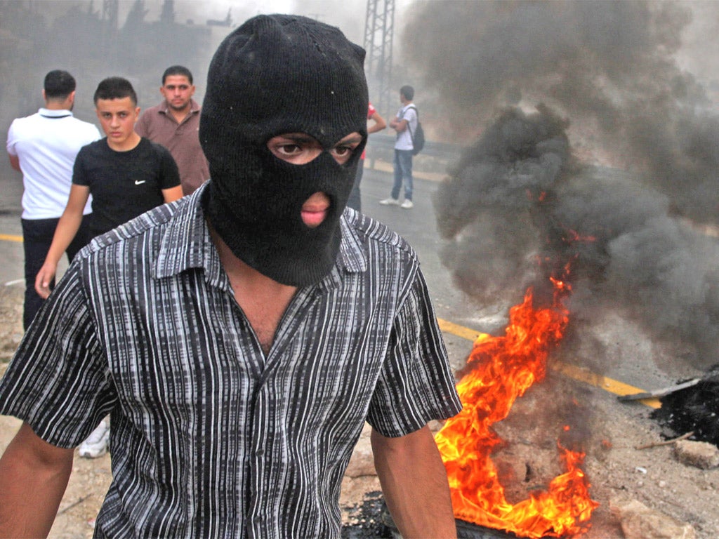 A masked demonstrator at a West Bank protest against the high cost of living