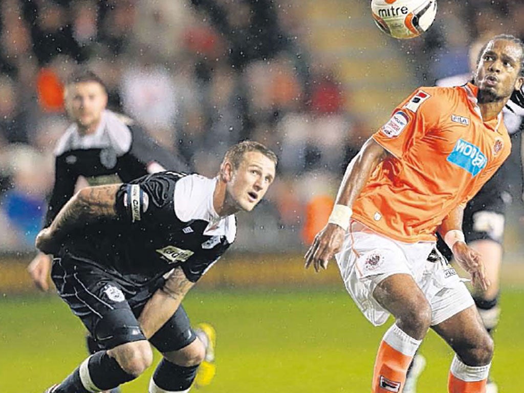 Nathan Delfouneso, of Blackpool, competes with Peter Clarke