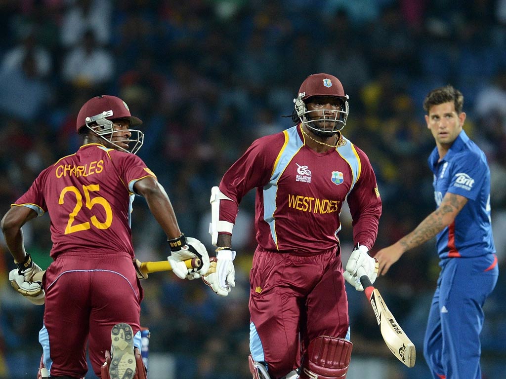 England cricketer Steven Finn (R) watches as West Indies cricketers Chris Gayle (C) and Johnson Charles (L) run between the wickets
