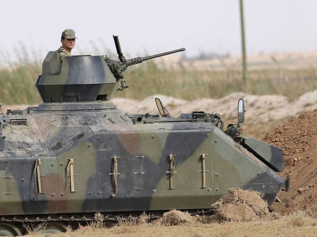 A Turkish soldier stands guard in an armoured personnel carrier on the Turkish-Syrian border