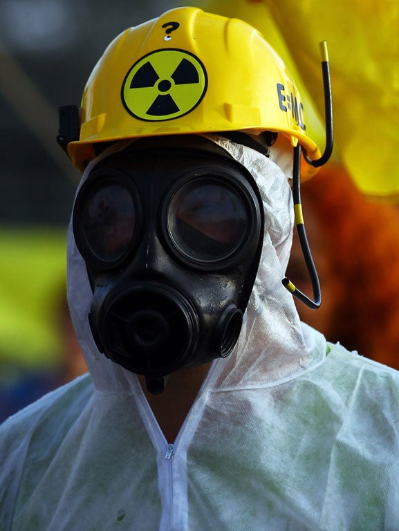 An anti-nuclear protestor wearing a gas mask stands with other demonstrators at the gates of Hinkley Point nuclear power station last year