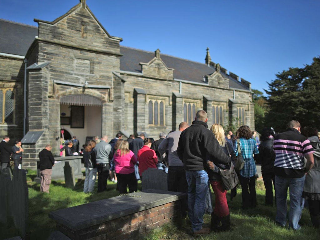 Members of the community of Machynlleth stand in the church yard of St Peter's Church for a service with prayers for missing five-year-old April Jones