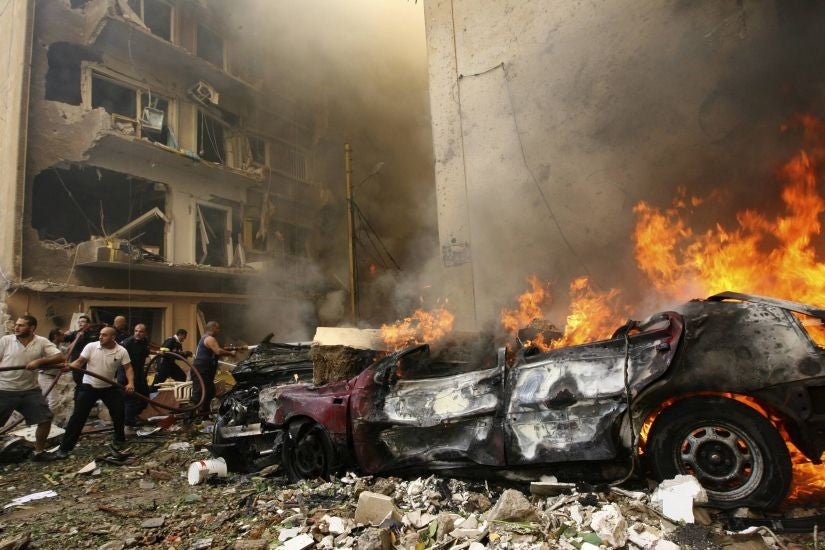 Firefighters try to extinguish a fire as a car burns at the scene of an explosion in Ashafriyeh, central Beirut