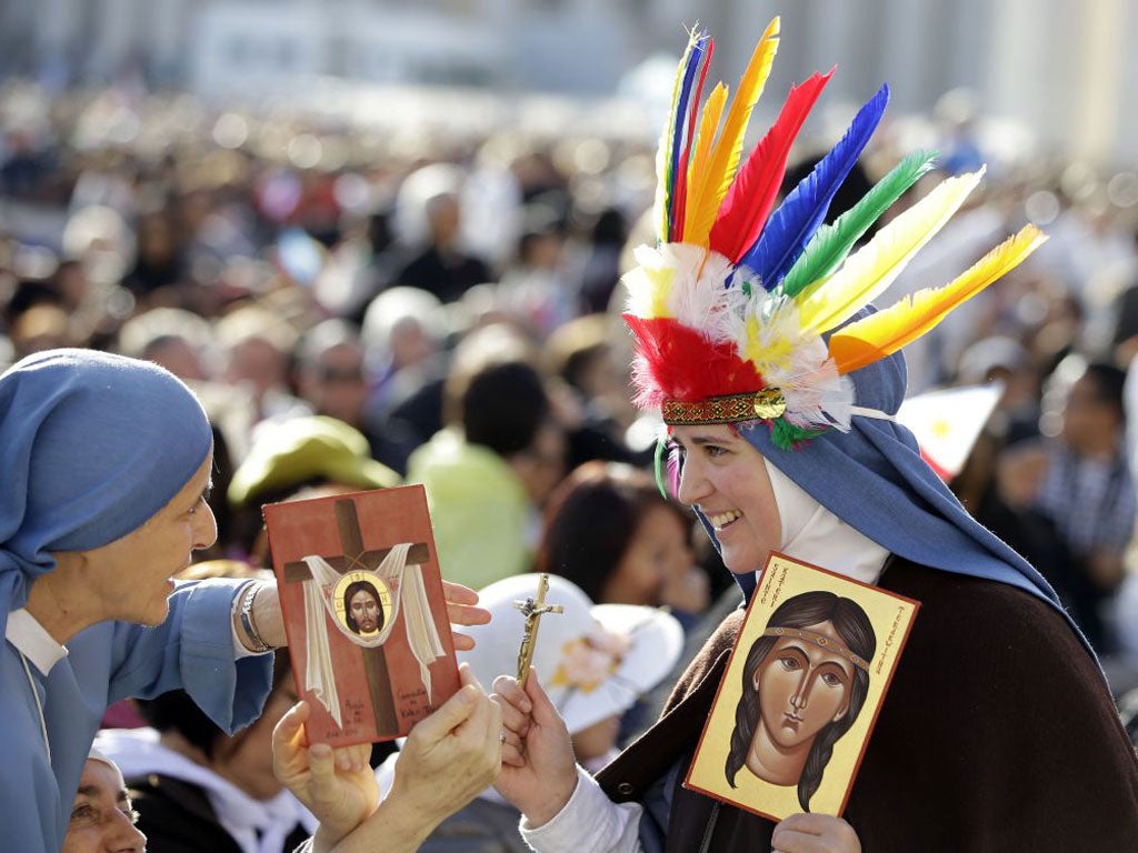 Nuns hold images of Kateri Tekakwitha, who died serving the church in Quebec in Canada, as they wait for the start of a canonisation ceremony celebrated by the Pope at the Vatican’s St Peter’s Square