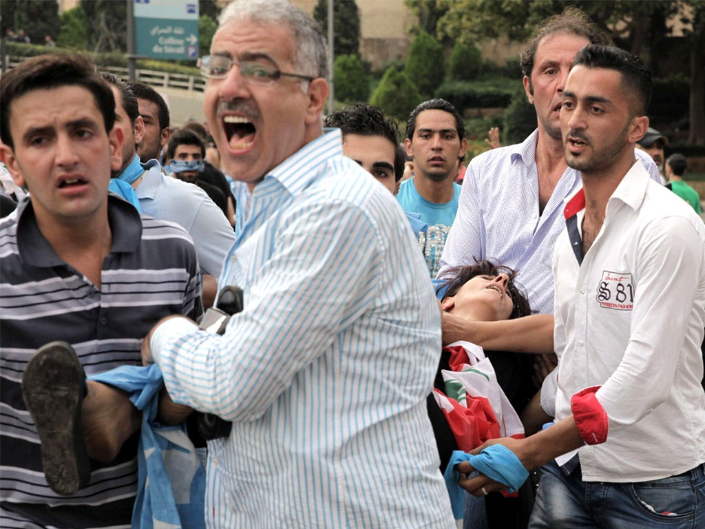 Supporters of the March 14 bloc carry a wounded woman during protests on Sunday