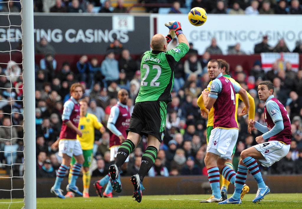 Aston Villa's USn goalkeeper Brad Guzan (C) punches the ball clear