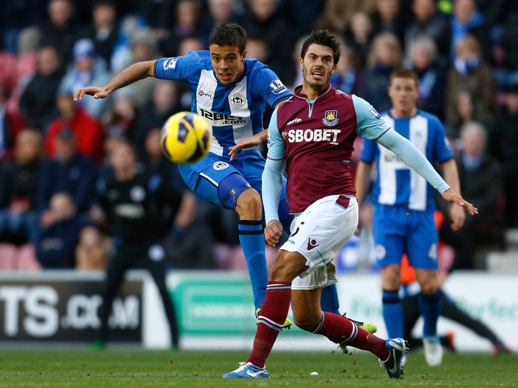 Franco Di Santo (L) of Wigan shoots at goal past James Tomkins of West Ham