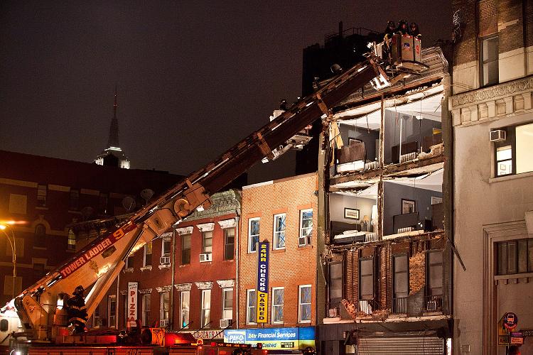 Firefighters evaluate the scene as Sandy destroys the front of a building in New York